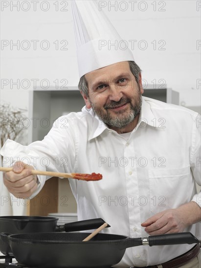 Chef offering taste of food in kitchen