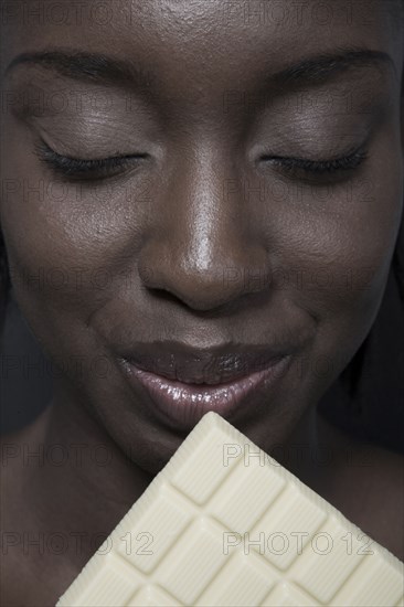 Close up of black woman eating bar of white chocolate