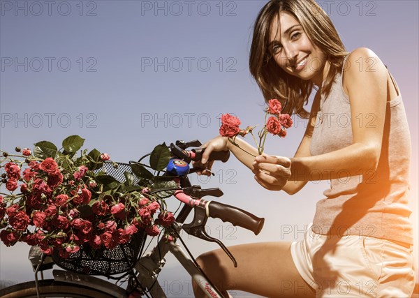 Woman on bicycle offering red flowers