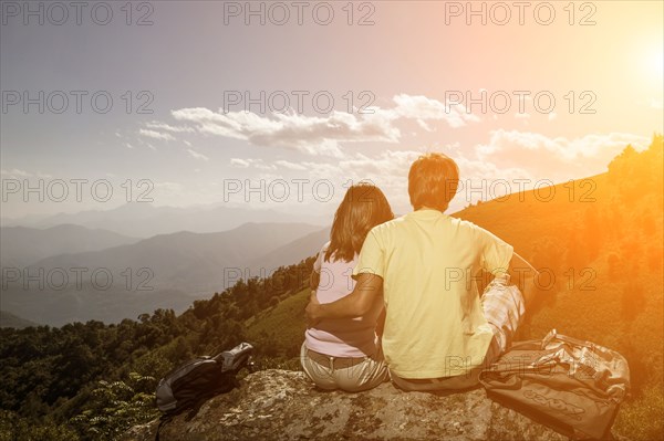 Couple sitting on rock admiring scenic view of mountain