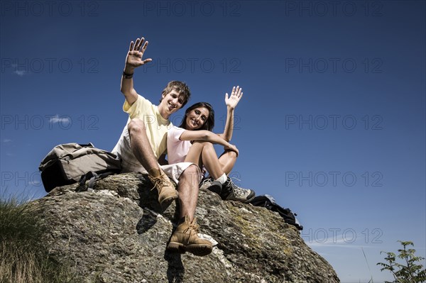 Smiling couple waving on rock