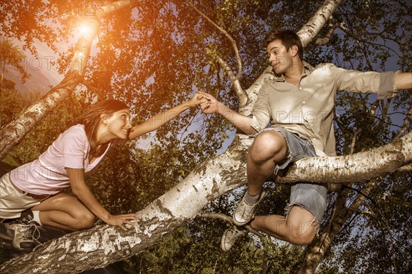 Couple holding hands on tree branch