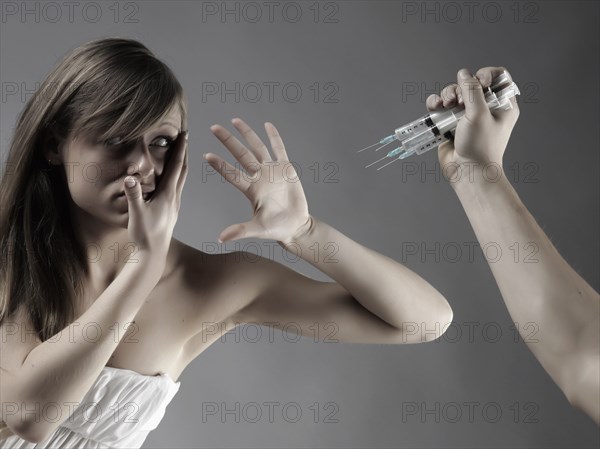 Caucasian woman protecting face from syringes