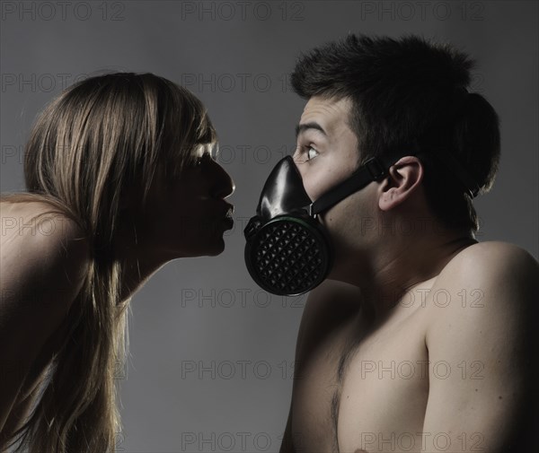 Naked Caucasian woman breathing on man wearing pollution mask