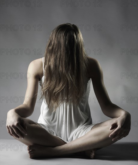 Caucasian woman sitting cross-legged with hair covering face