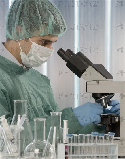 Caucasian scientist using microscope in laboratory