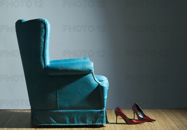 Red high heels near blue armchair