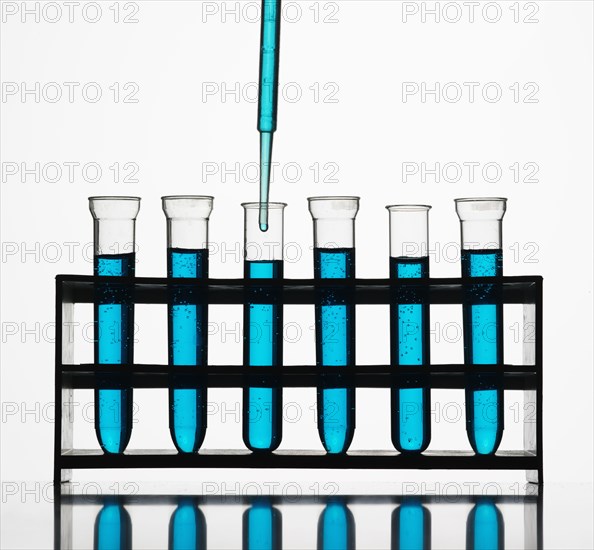 Pipette dripping blue liquid into test tubes