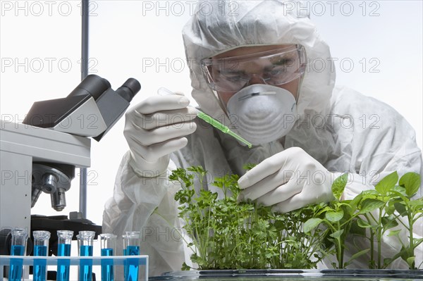 Caucasian scientist wearing clean suit examining seedling