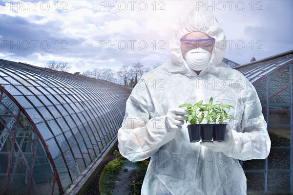 Caucasian scientist wearing clean suit examining seedling