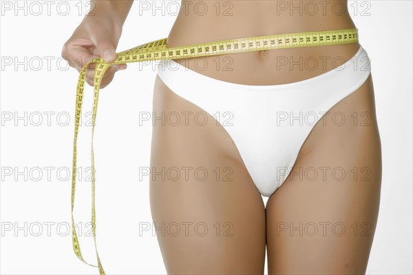 Caucasian woman measuring waist