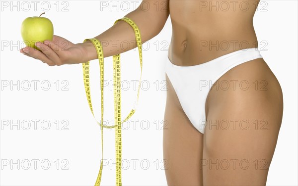 Caucasian woman holding green apple and measuring tape