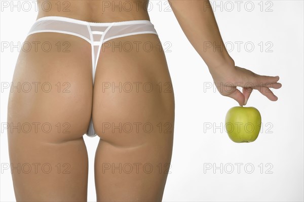 Caucasian woman wearing panty holding green apple