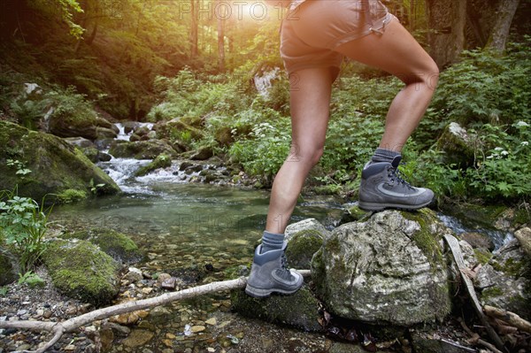Legs of Caucasian woman hiking over river