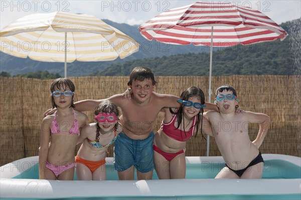 Smiling Caucasian children posing in inflatable swimming pool