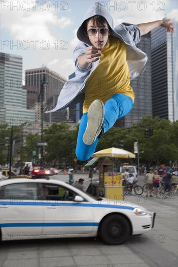 Caucasian man jumping over police car in city