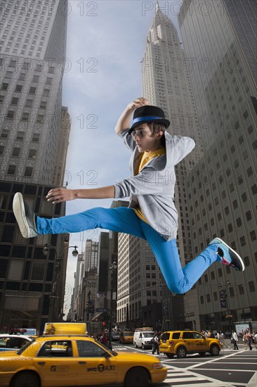 Caucasian man jumping over taxis in city