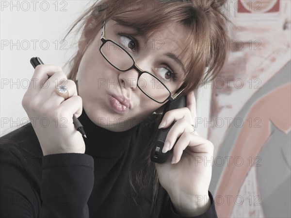 Caucasian businesswoman talking on telephone making a face