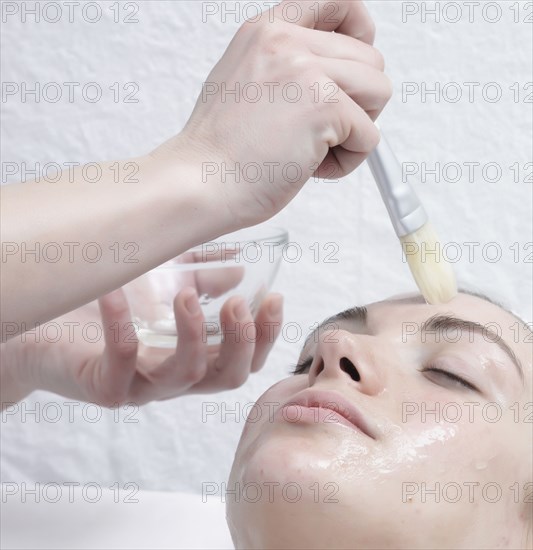 Caucasian woman receiving facial beauty treatment