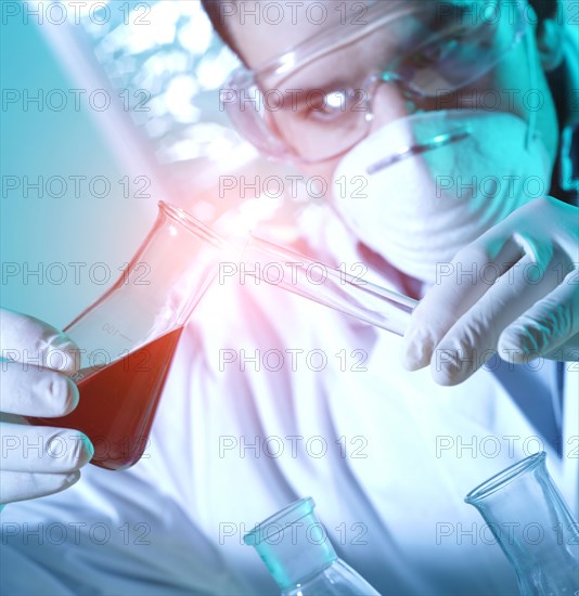 Caucasian scientist pouring red liquid into test tube