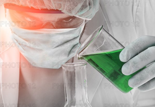 Caucasian scientist pouring green liquid into beaker
