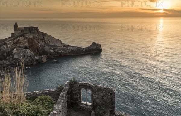 Stone building near ocean at sunset