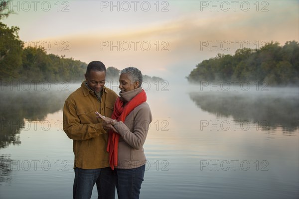 Older couple looking at ring at foggy river at sunrise