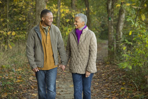 Older couple holding hands walking in forest