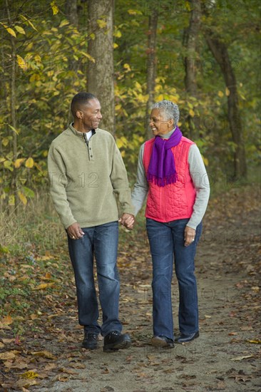 Older couple holding hands walking in forest