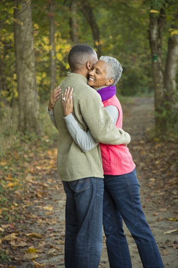 Older couple hugging in forest