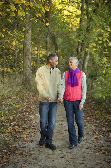 Older couple holding hands walking in forest