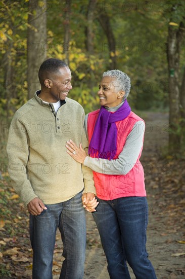 Older couple holding hands walking in forest