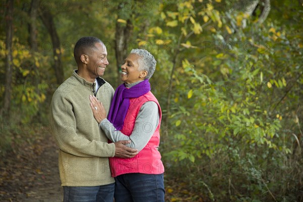 Older couple holding hands walking in forest