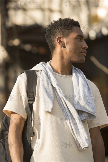 Mixed Race man with backpack and shirt draped over shoulders