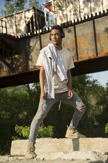 Mixed Race man with shirt draped over shoulders listening to headphones