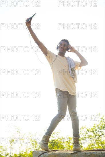 Mixed Race man with shirt draped over shoulders listening to headphones