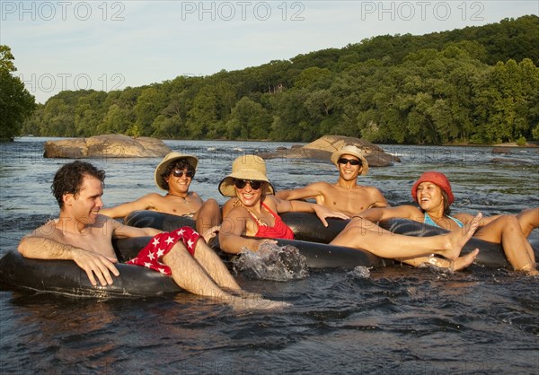 Friends floating on river in inner tubes