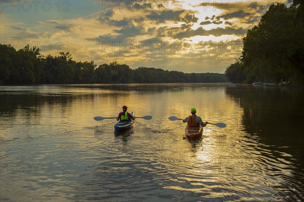 Couple kayaking in river at sunset