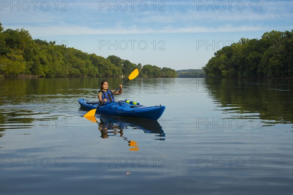 Mixed Race woman kayaking in river