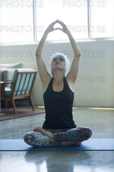Woman sitting on floor stretching arms