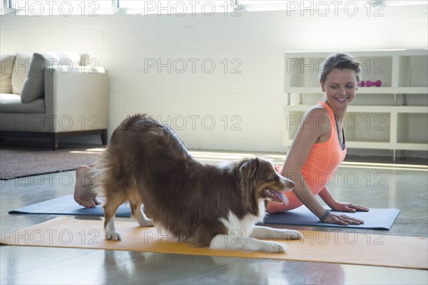Caucasian woman and dog doing yoga stretching backs