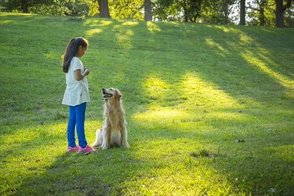 Hispanic girl training dog on hill