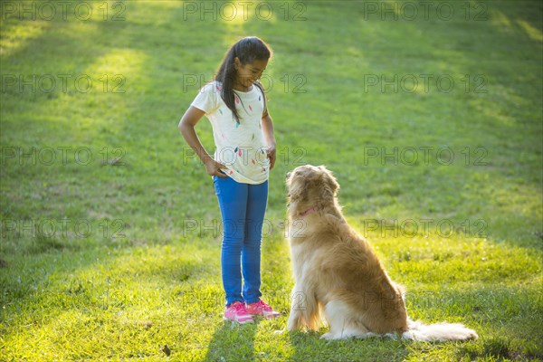 Hispanic girl training dog on hill