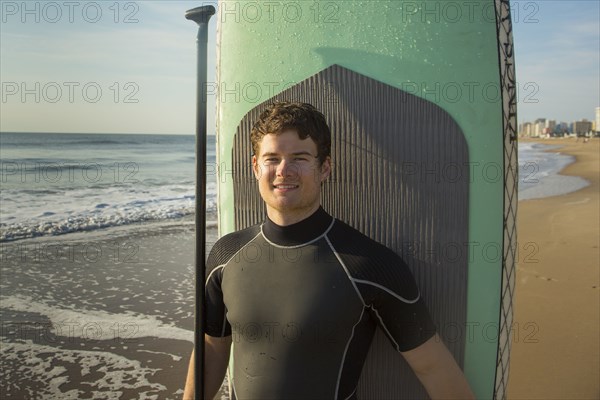 Man posing with paddleboard on beach