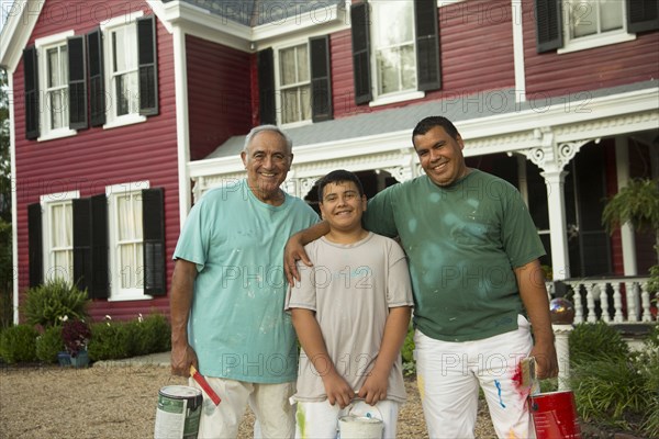 Smiling Hispanic men and boy posing with paint cans