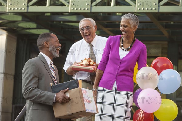 Co-workers celebrating with retiring man carrying belongings