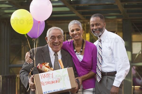 Co-workers posing with retiring man carrying belongings