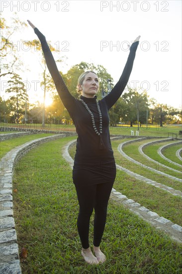 Caucasian woman meditating on grass in park