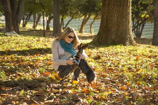 Caucasian woman petting dog in park
