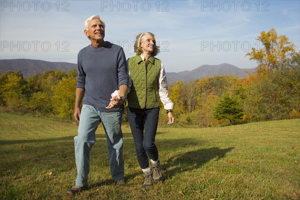 Older Caucasian couple walking in field